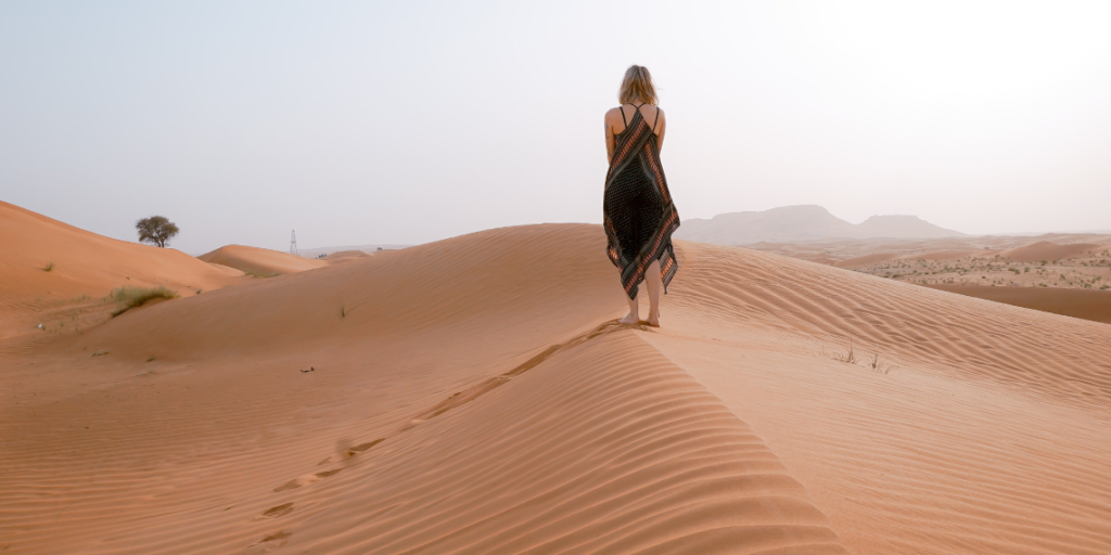 Woman walking on desert dunes in Dubai
