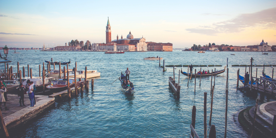 A gondola sailing into a canal from the Venice lagoon