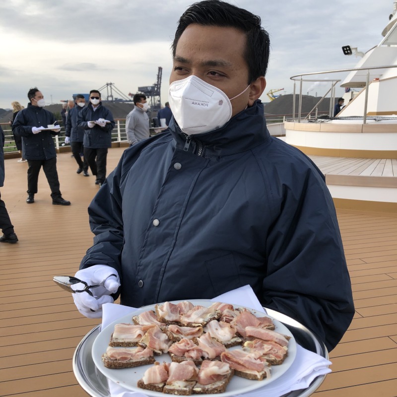 Crew member serving rye bread toppe with cured bacon