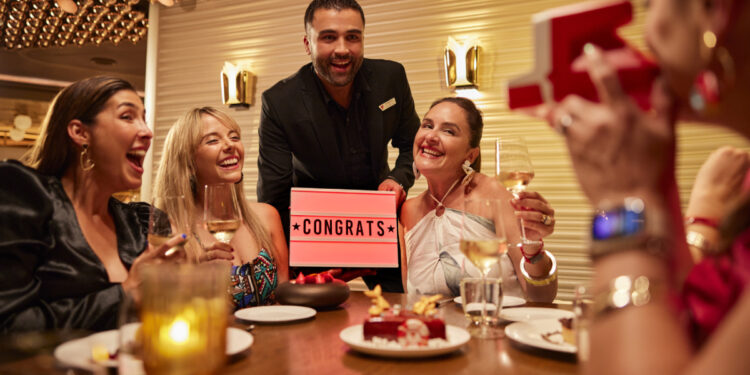 Group of friends celebrating at The Wake restaurant onboard a Virgin Voyages ship.