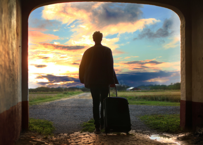 Person pulling a suitcase through an archway