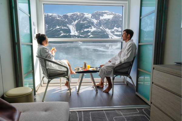 A couple enjoying views of Alaska from an infinite veranda stateroom on Celebrity Cruises' Celebrity Edge