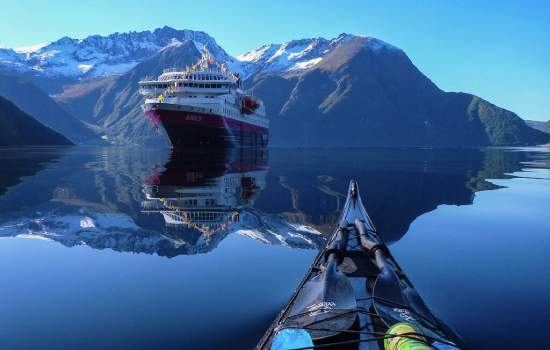Kayaking towards Hurtigruten ship MS Nordlys on Hjørundfjord