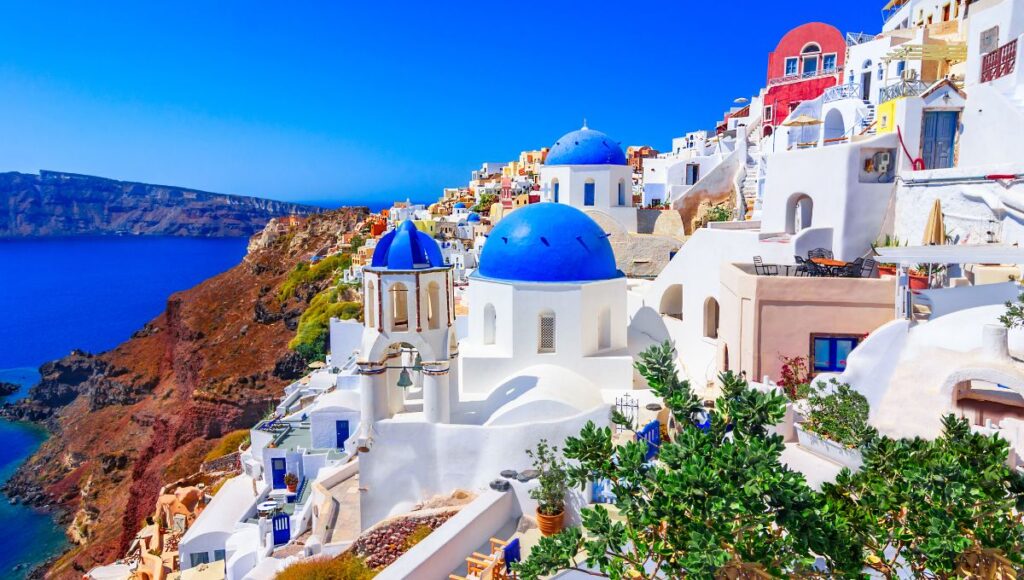 Oia village in Santorini with white buildings and blue domes overlooking the caldera