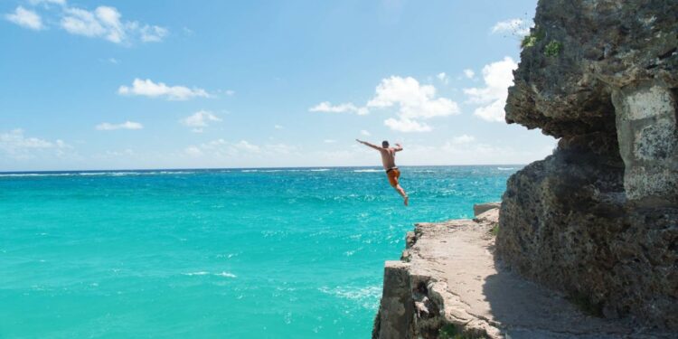 Person cliff jumping into the sea in Barbados during a Southern Caribbean cruise