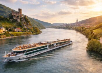 Luxury river cruise ship sailing along the Danube River past castles, vineyards and historic European towns at sunset