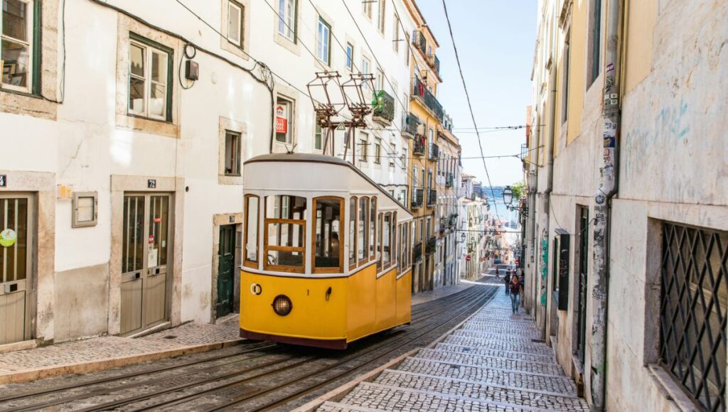 A traditional yellow tram on a cobbled Lisbon street, the embarkation port for the Azamara Lisbon to Lisbon cruise itinerary