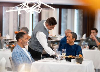Azamara dining review: waiter serving dinner to guests in the main restaurant on Azamara Journey