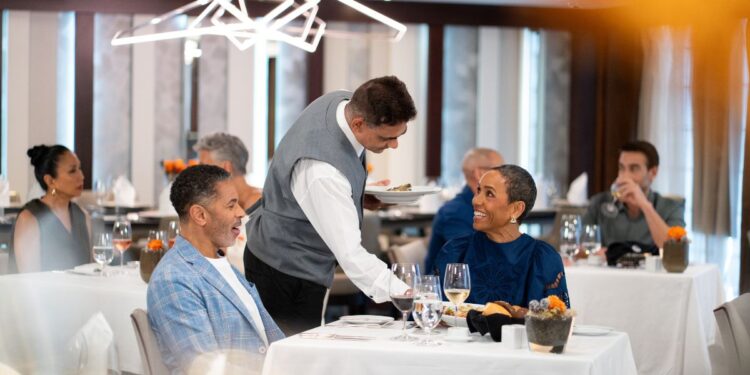 Azamara dining review: waiter serving dinner to guests in the main restaurant on Azamara Journey