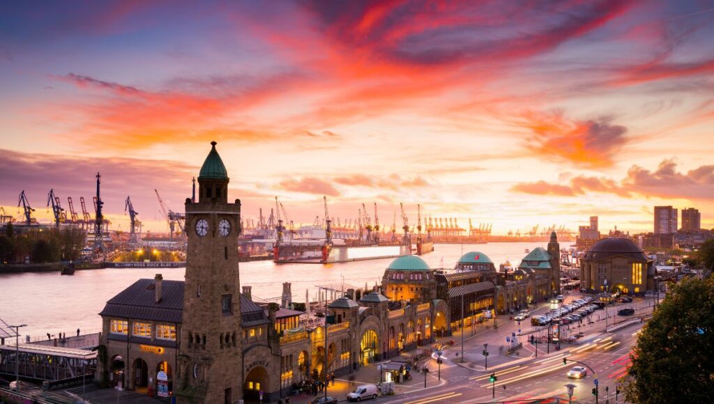 Sunset over Hamburg Harbour and the historic Landungsbrücken waterfront in Germany.