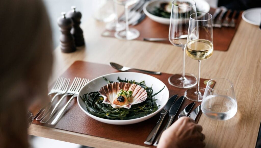 Fine dining seafood dish with white wine served aboard a Norwegian coastal cruise ship.