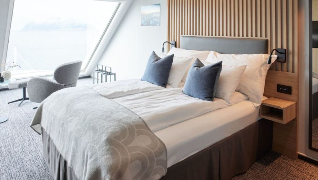 Modern Havila Voyages cabin with double bed, large window and contemporary Scandinavian interior.