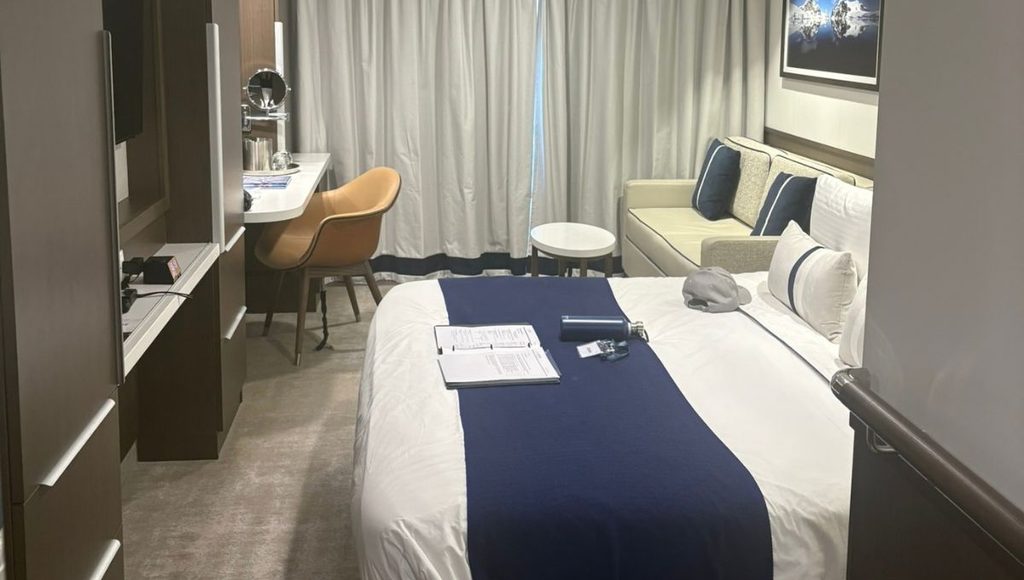 Balcony stateroom on Douglas Mawson with the bed, desk and seating area in one view