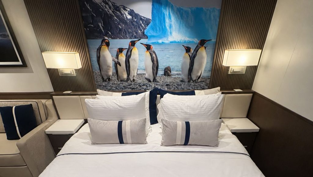 Bed in a Douglas Mawson stateroom beneath a king penguin mural headboard