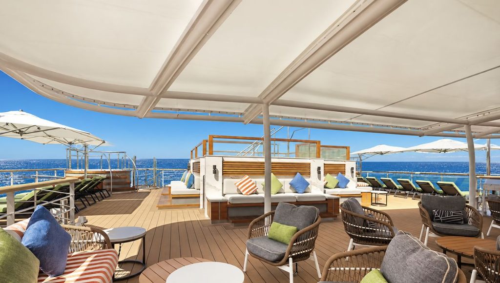 Sun deck on Douglas Mawson with hot tubs, loungers and shaded seating overlooking the sea