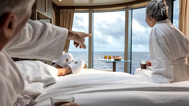 Couple looking out of a panoramic window in their Veranda Suite onboard Seabourn Venture