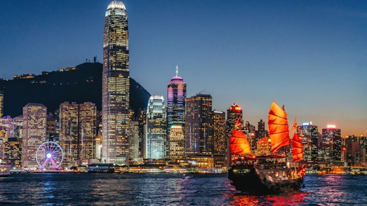 Traditional sail boat cruising in front of the skyline of Hong Kong
