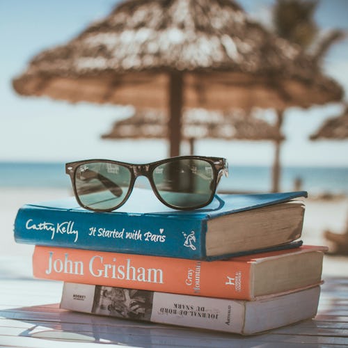 Sunglasses on top of a 3 books on a beach