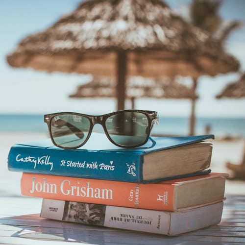 Sunglasses on top of a 3 books on a beach