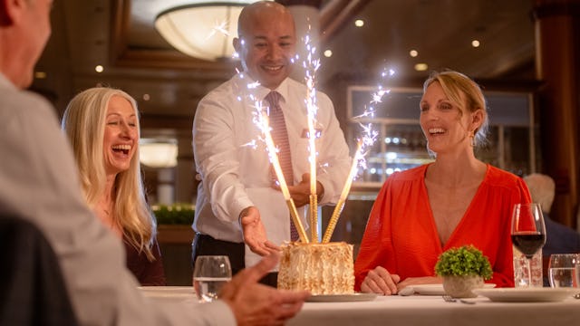 Guest being presented with a baked alaska onboard Ambassador Cruise Line's ship