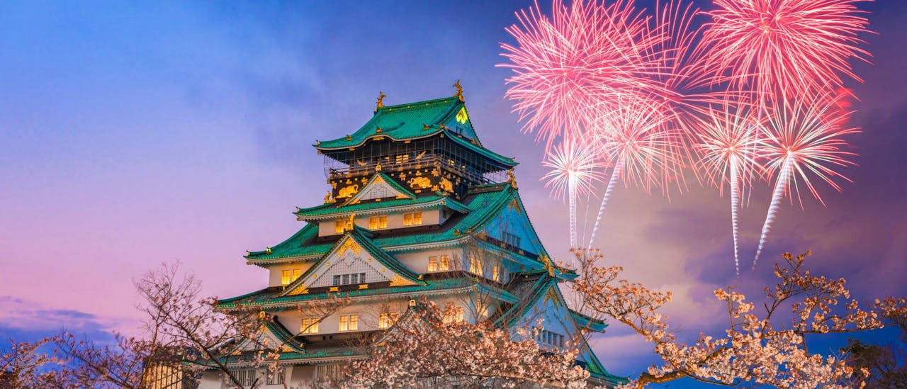 Castle in Osaka, Japan with fireworks in the background.
