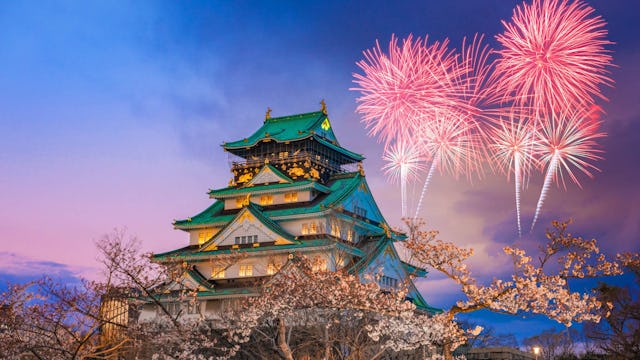 Castle in Osaka, Japan with fireworks in the background.