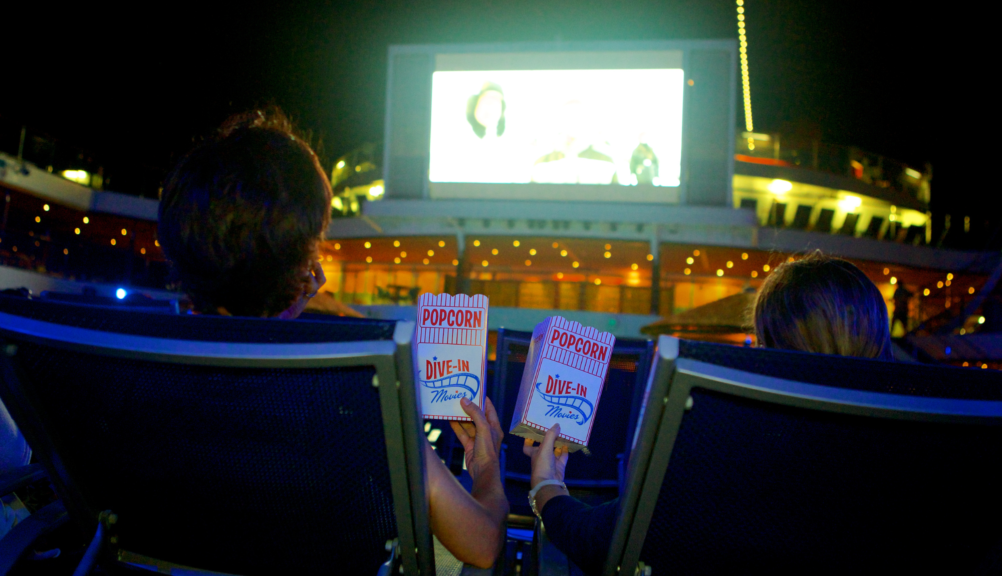 Two people enjoying popcorn and a movie under the stars