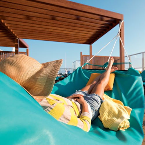 Woman relaxing on a hammock in the adult-only serenity onboard a Carnival ship.