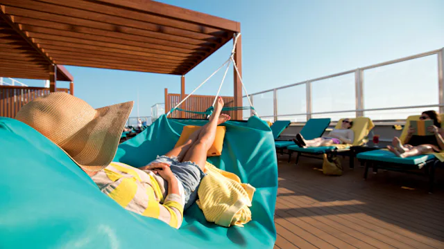 Woman relaxing on a hammock in the adult-only serenity onboard a Carnival ship.