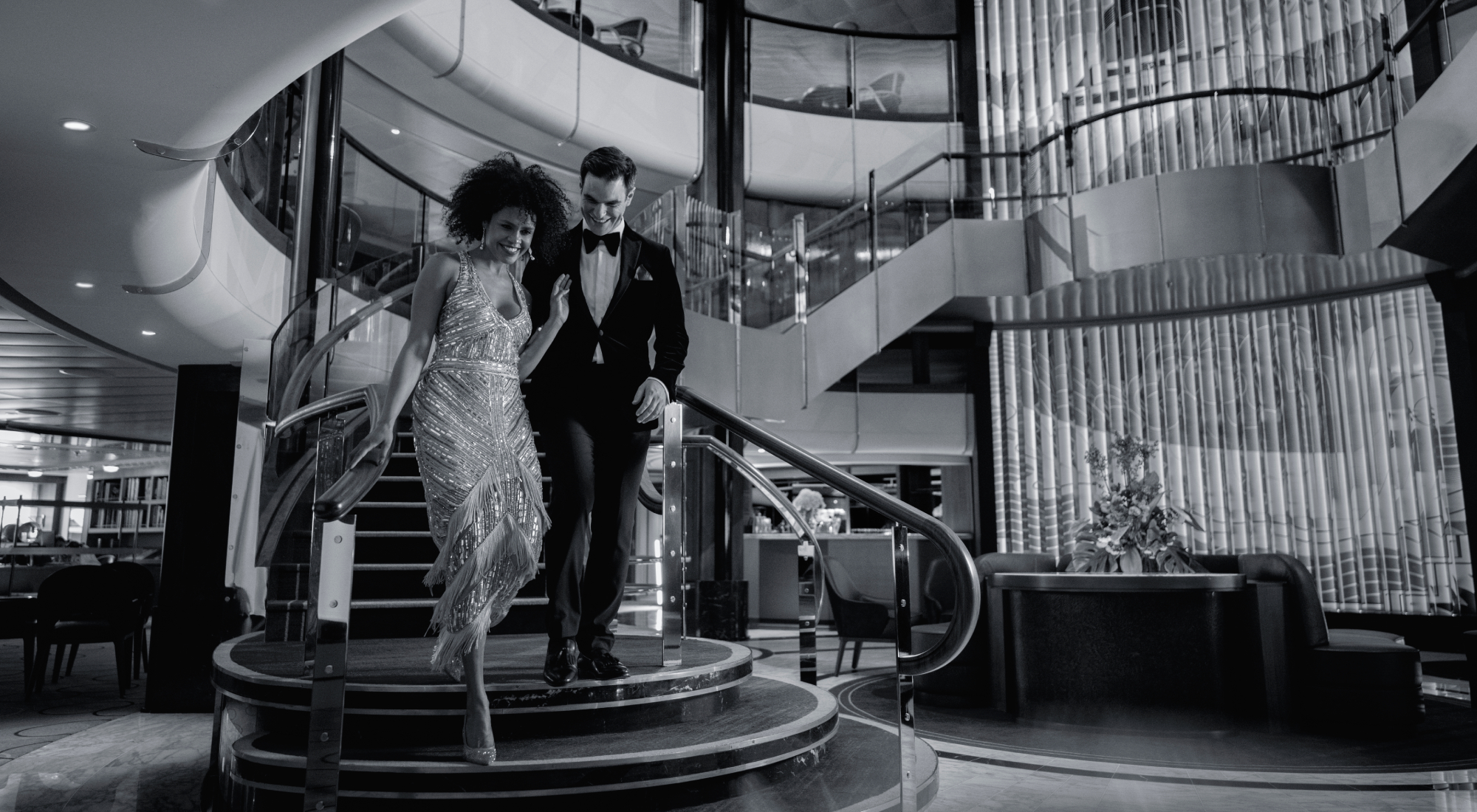 Guests walking down the stairs of the Grand Lobby onboard Cunard's Queen Anne