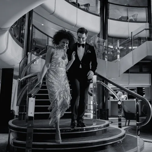 Guests walking down the stairs of the Grand Lobby onboard Cunard's Queen Anne