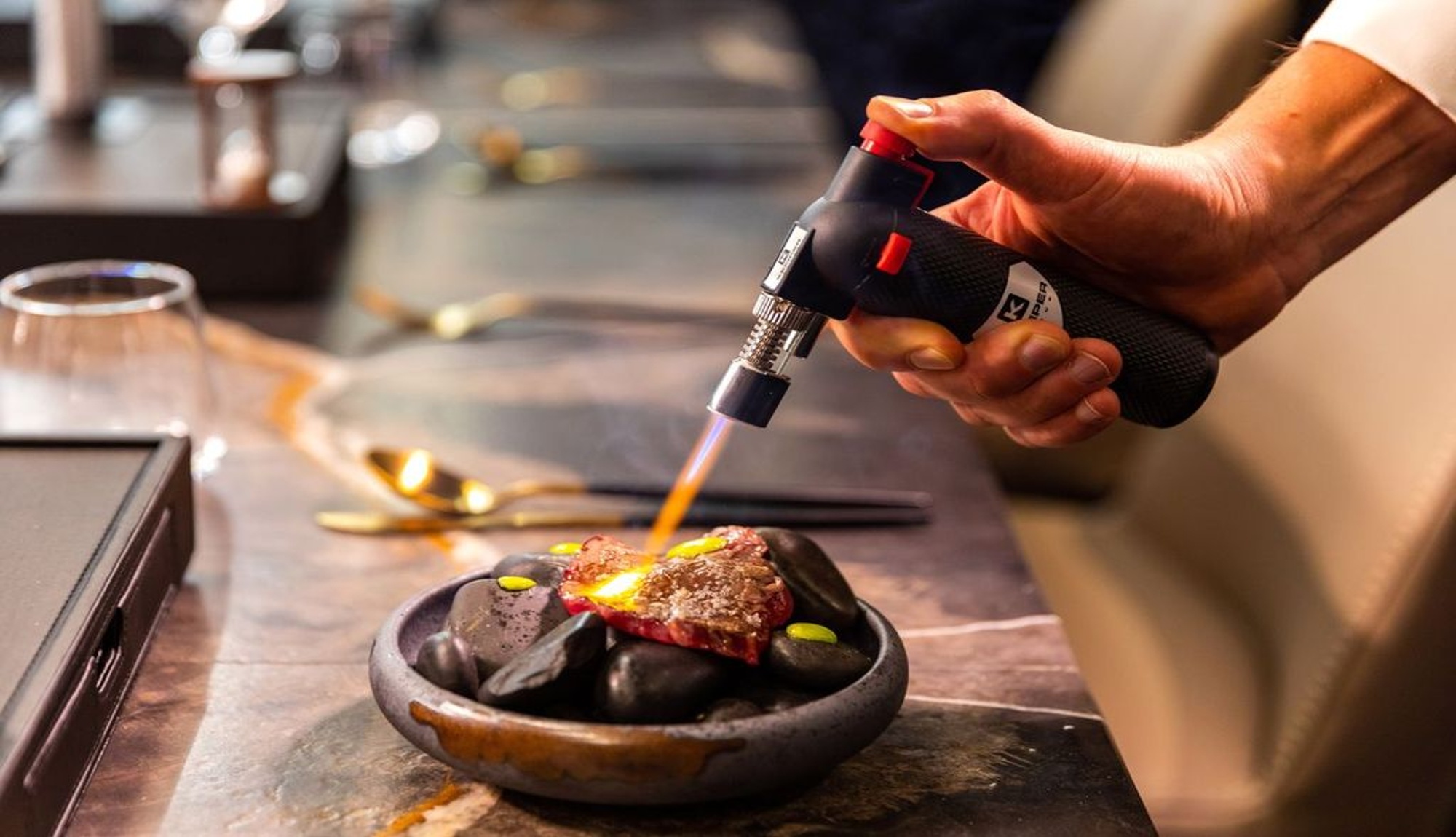 Steak cooked on hot stones with a blow torch