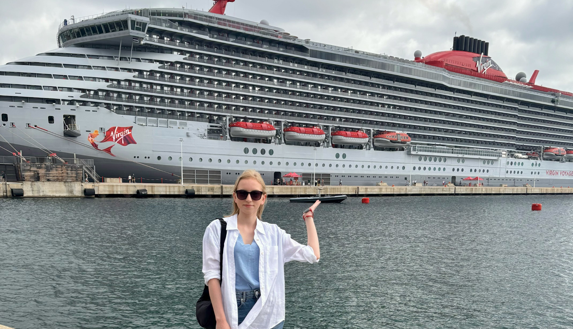 Monika on holiday in front of a Virgin Voyages ship