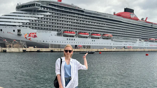 Monika on holiday in front of a Virgin Voyages ship