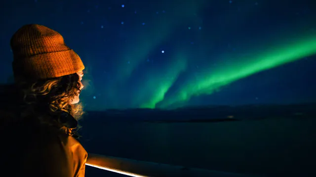 Hurtigruten Northern Lights Cruises - Guest watching the Aurora Borealis from a Hurtigruten ship in Alta, Norway