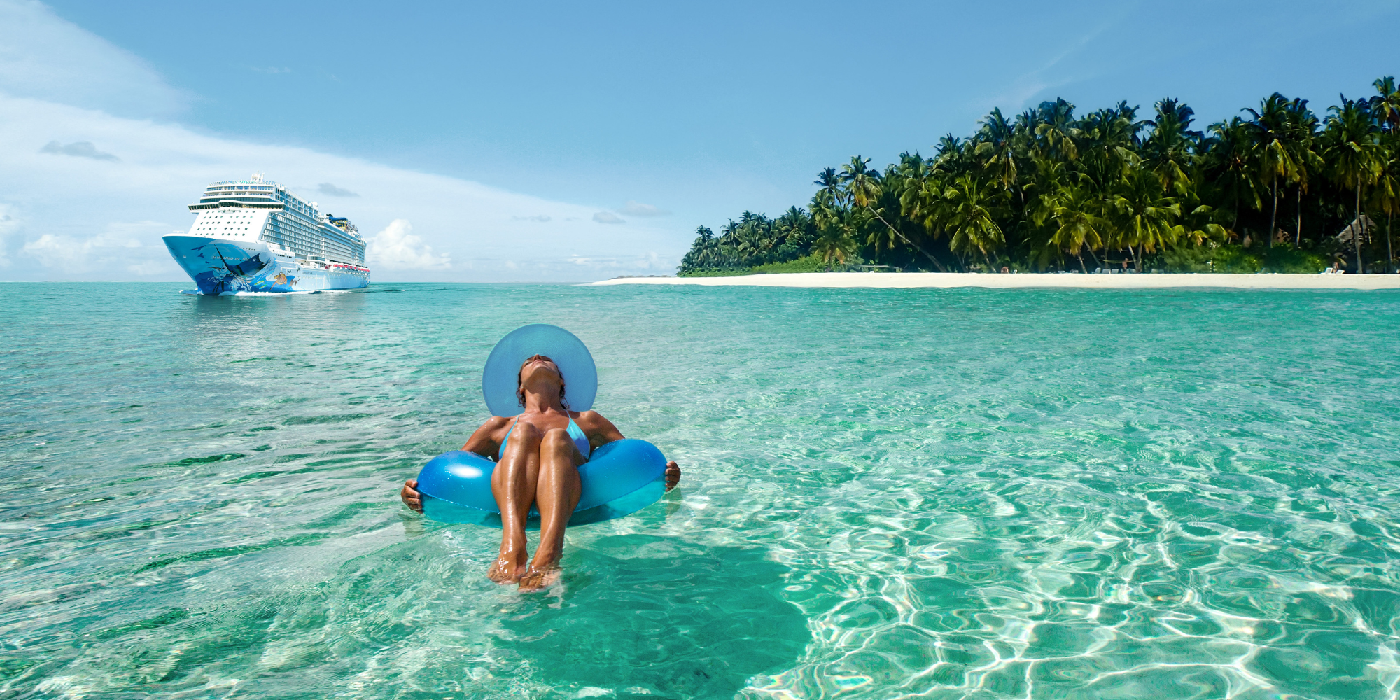 Woman lying on an inflatable in the Caribbean ocean with an NCL ship in the background