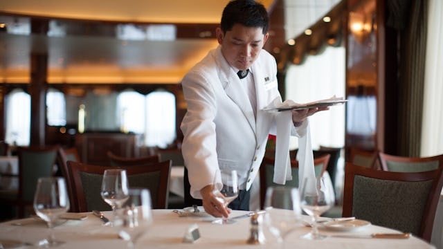 Waiter plating up tables in the Queens Grill onboard Queen Victoria