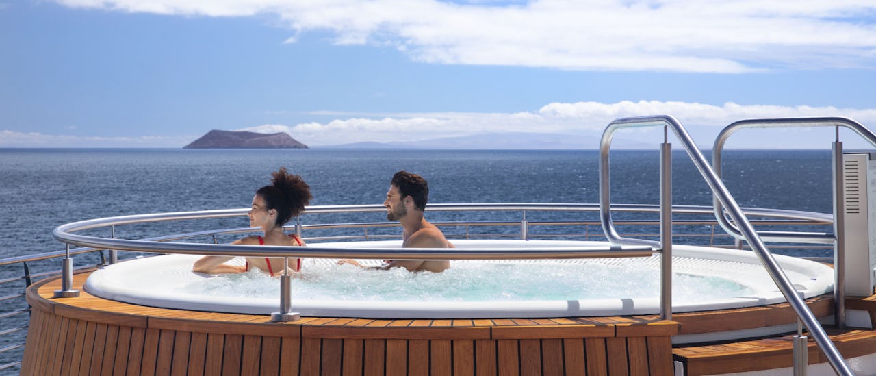 Celebrity Flora guests relaxing in a hot tub enjoying views of the Galapagos Islands.