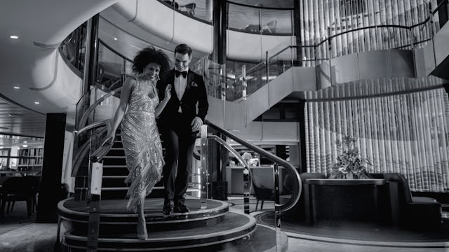Guests walking down the stairs of the Grand Lobby onboard Cunard's Queen Anne